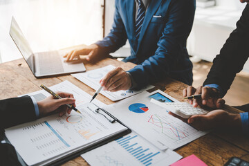 Young colleagues discuss business and analytical price charts using calculators and laptops to calculate financial, tax, accounting, statistics and analytical research ideas.