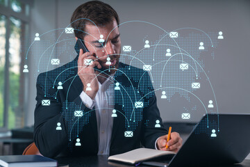 Smiling businessman talking holding using smartphone typing at office workplace with notebook. Concept of distant work, business education. Social network and media net.