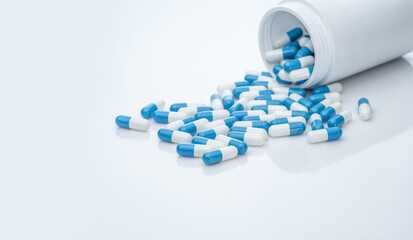 Poster - Blue-white antibiotic capsule pills spread out of plastic drug bottles. Antibiotic drug resistance. Prescription drugs. Healthcare and medicine. Pharmaceutical industry. Pharmacy product. Medication.