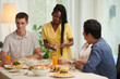 © DragonImages - Smiling young woman bringing silverware to dinner table
