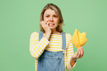 Wall Mural - Sick unhealthy ill allergic woman has red watery eyes runny stuffy sore nose suffer from allergy trigger symptoms hay fever hold napkin biting nails isolated on plain green background studio portrait.