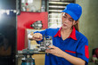 © SKW - A female diesel engine mechanic in a blue uniform is working at the garage. Inspect and maintain the fuel pressure booster pump system and common rail injectors.