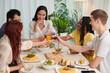 © DragonImages - Happy group of friends toasting over dinner table