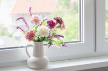 Pink And Purple Summer Flowers In White Jug On Windowsill