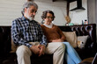 Senior couple sitting on sofa using laptop. Retirement and happy senior lifestyle concept.