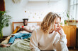 © Westend61 - Sad woman on bed with boyfriend using phone in background
