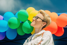Blond Woman Wearing Eyeglass In Front Of Rainbow Colured Balloons