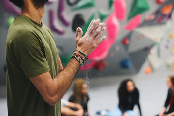 Close Up Of Man Rubbing Hands With Chalk Waiting To Try Climbing Wall At Indoor Centre