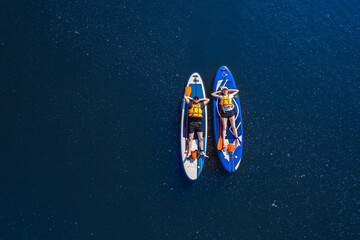 Funny man and woman floats on supboard on lake, top view from drone. Concept Summer active sport on water