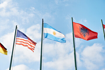 USA, Argentina and Albania flags on sky