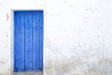 White Wall With A Blue Wooden Door