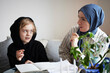 © Johnér - Mother wearing hijab helping son doing homework