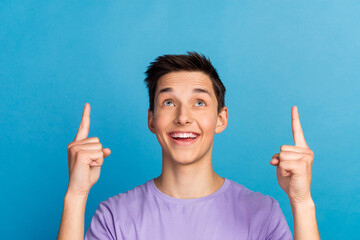 Wall Mural - Handsome smiling man pointing away up follow adverts empty space on blue color background