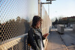 © Johnér - Young woman leaning on fence and using cell phone