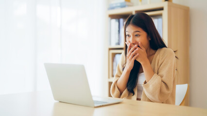 Funny euphoric young asian woman celebrating winning or getting ecommerce shopping offer on computer laptop. Excited happy girl winner looking at notebook celebrating success