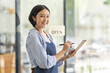 © David - Startup successful small business owner sme beauty girl stand with tablet smartphone in coffee shop restaurant. Portrait of asian tan woman barista cafe owner. SME entrepreneur seller business concept