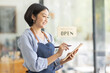 © David - Startup successful small business owner sme beauty girl stand with tablet smartphone in coffee shop restaurant. Portrait of asian tan woman barista cafe owner. SME entrepreneur seller business concept