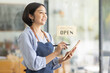 © David - Startup successful small business owner sme beauty girl stand with tablet smartphone in coffee shop restaurant. Portrait of asian tan woman barista cafe owner. SME entrepreneur seller business concept