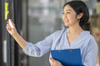 © David - Young Creative business asian woman writing on sticky notes on a glass wall, female colleague looking.