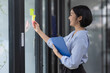 © David - Young Creative business asian woman writing on sticky notes on a glass wall, female colleague looking.