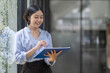 © David - Boring young business Asian woman holding document file and looking at camera stand on a workplace office.