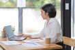 © David - Asian Businesswoman Using laptop computer and working at office with calculator document on desk, doing planning analyzing the financial report, business plan investment, finance analysis concept.