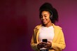 © Creative Clicks - Portrait of an Afro-American girl listening to music and wearing headphones and looking at her phone in a pink background