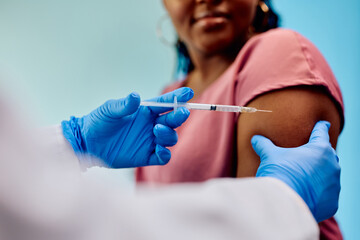 Wall Mural - Close up of doctor giving vaccine to black woman at clinic.