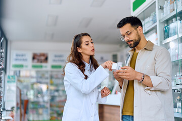 Poster - Young pharmacist advising her customer in buying medicine in pharmacy.