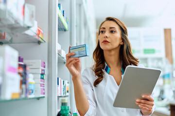 Wall Mural - Female pharmacist using digital tablet while going through inventory in pharmacy.