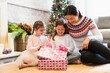 Mother and daughters opening Christmas gifts on living room floor