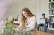 © KOTO - Smiling woman texting with cell phone at dining table