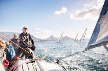 Wall Mural - Man adjusting sailboat rigging on sunny ocean