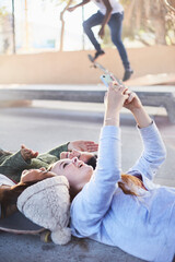 Wall Mural - Teenage girls laying taking selfie with camera phone at skate park