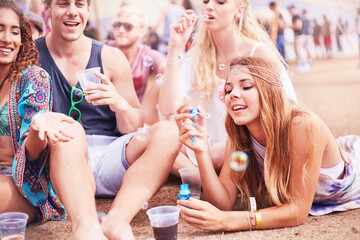 Wall Mural - Young friends hanging out blowing bubbles at music festival