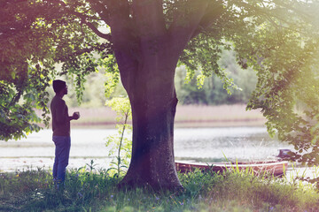 Canvas Print - Man drinking coffee below tree at idyllic lakeside