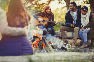 Wall Mural - Friends playing guitar and drinking beer at campfire