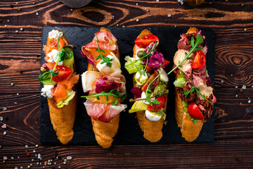 Wall Mural - Various bruschettas with beef slices, capers, cherry tomatoes, mozzarella, salmon, cucumber, lettuce.