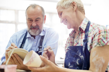 Senior couple painting pottery in studio