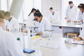 college students using microscope conducting scientific experiment in laboratory