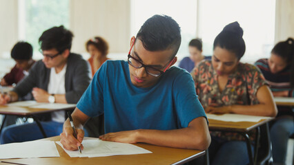 Wall Mural - Male college student taking test at desk in classroom