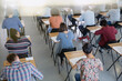 © KOTO - College students taking test at desks in classroom