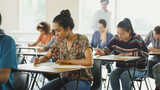 Fototapeta Miasto - College students taking test at desks in classroom