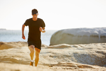 Wall Mural - Male triathlete running on sunny rocky trail