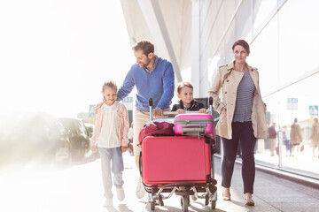 Wall Mural - Family with luggage cart walking outside airport