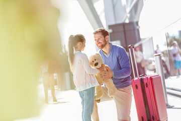 Wall Mural - Father and daughter with teddy bear and suitcase outside airport