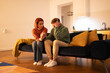 © DimaBerlin - Emotional support in relationship. Young woman wife holding hand of stressed upset husband, sitting on couch at home, showing understanding, compassion and love to partner going through hard times