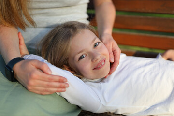 Wall Mural - The child girl lies on her mother's lap, resting in the park.