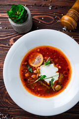 Sticker - Solyanka soup with ham, meat, olives, tomatoes, sour cream, lemon, pickled cucumbers, onions and herbs in a plate.