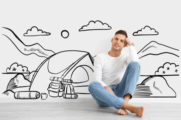 Sticker - Barefooted man sitting near light wall with drawn camping tent and mountains